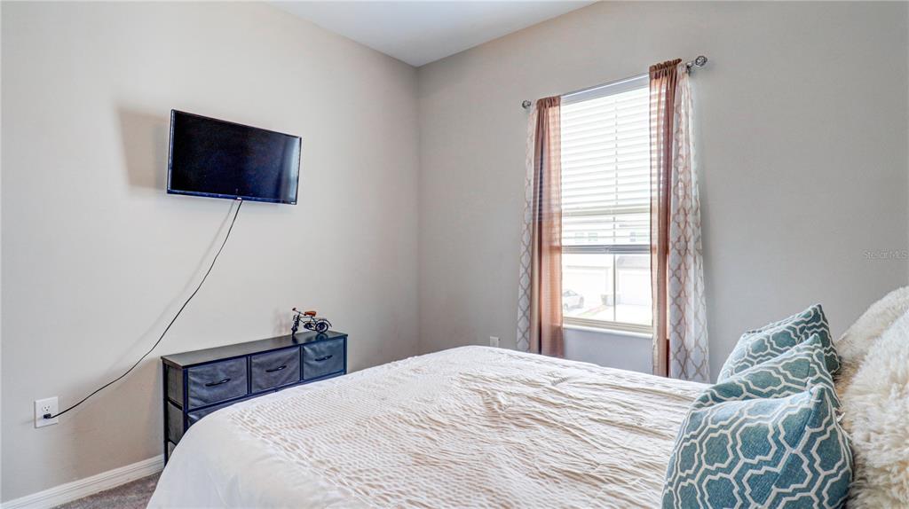 31632 Blue Passing Loop Wesley Chapel, FL 33545 - Photo 39 of 48 a bedroom with a bed and a flat screen tv