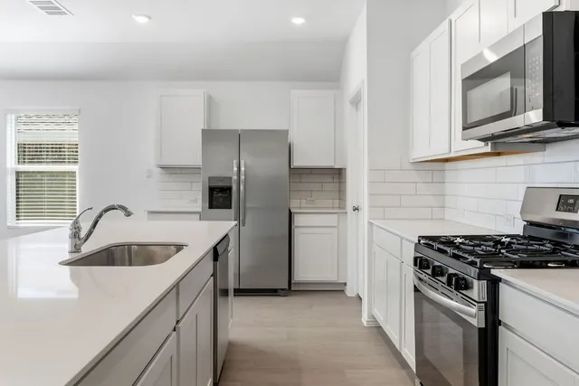 a kitchen with stainless steel appliances granite countertop a sink stove and microwave