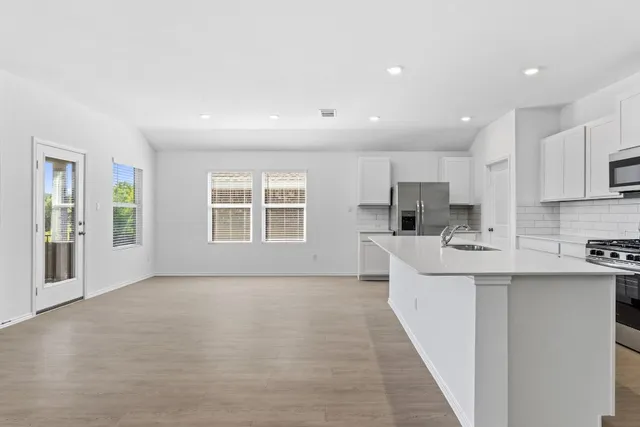 a large white kitchen with kitchen island a sink a stove a refrigerator and a window