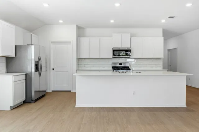 a white kitchen with a refrigerator sink and cabinets