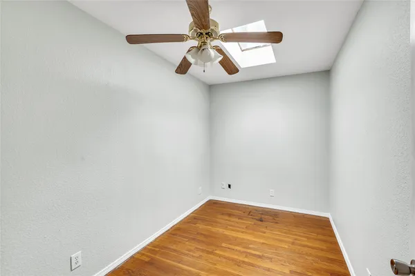 an empty room with a ceiling fan and wooden floor