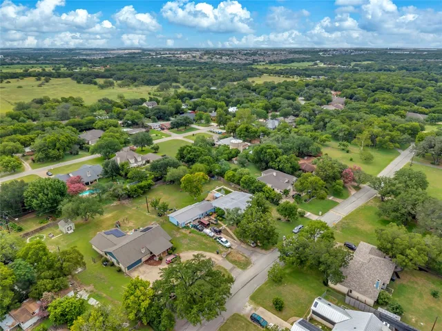 an aerial view of residential houses with outdoor space and trees