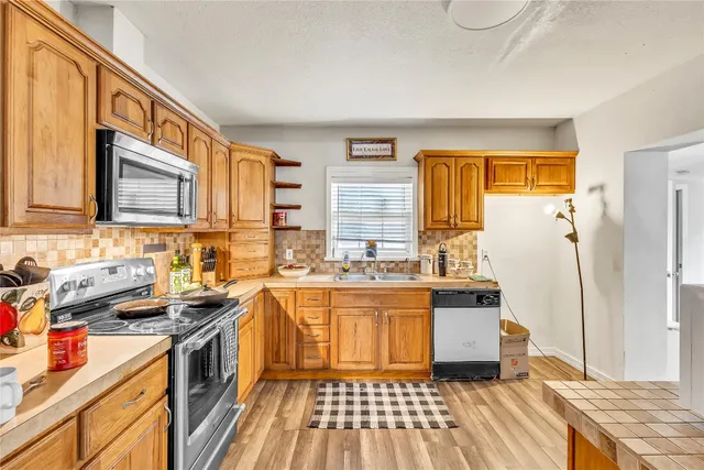 a kitchen with stainless steel appliances granite countertop a stove a sink dishwasher and a refrigerator with wooden cabinets