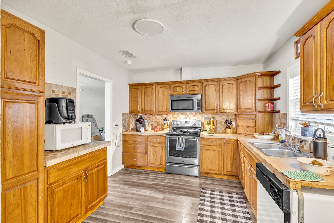 11909 Bluebonnet Lane Manchaca, TX 78652 - Photo 10 of 30 a kitchen with stainless steel appliances granite countertop a stove top oven a sink dishwasher and a refrigerator with wooden cabinets
