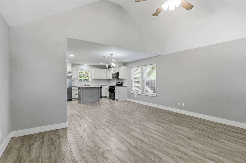 318 Munson Street Denison, TX 75021 - Photo 4 of 21 an empty room with wooden floor kitchen view and a window