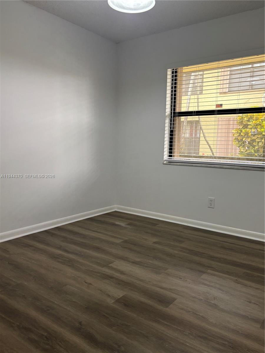 10023 Winding Lake Road, Unit 101 Sunrise, FL 33351 - Photo 11 of 19 a view of an empty room with wooden floor and a window