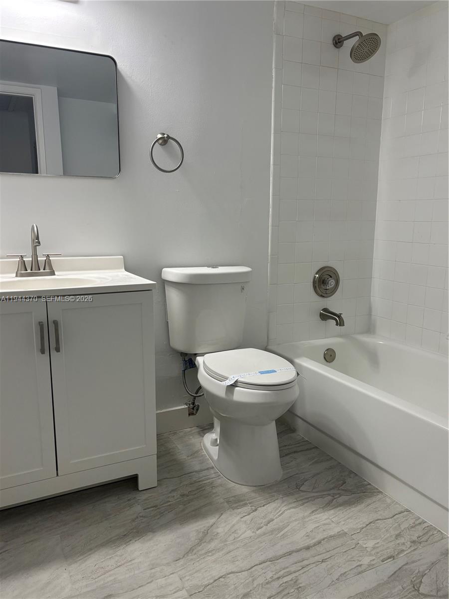 10023 Winding Lake Road, Unit 101 Sunrise, FL 33351 - Photo 14 of 19 a white toilet sitting next to a bathroom sink