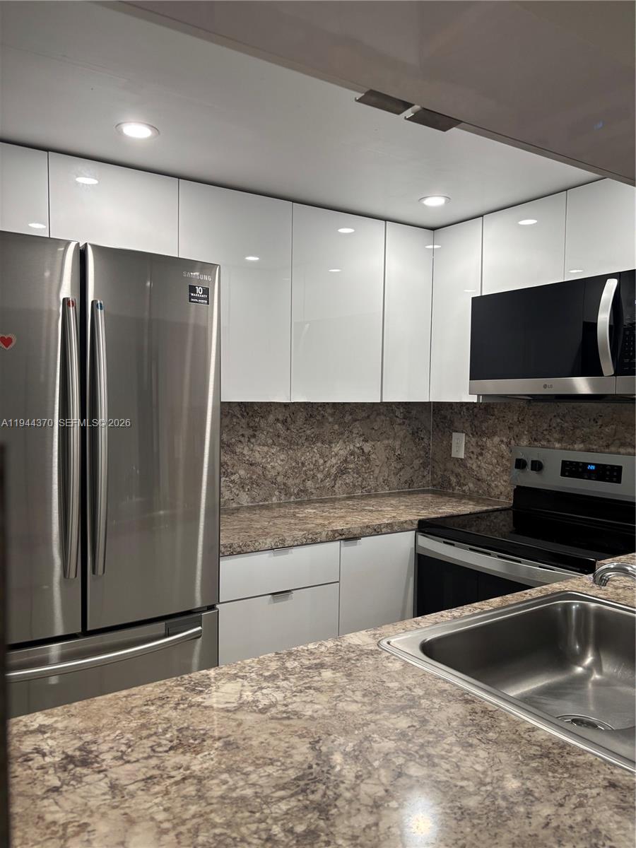 10023 Winding Lake Road, Unit 101 Sunrise, FL 33351 - Photo 3 of 19 a kitchen with granite countertop a refrigerator and a sink