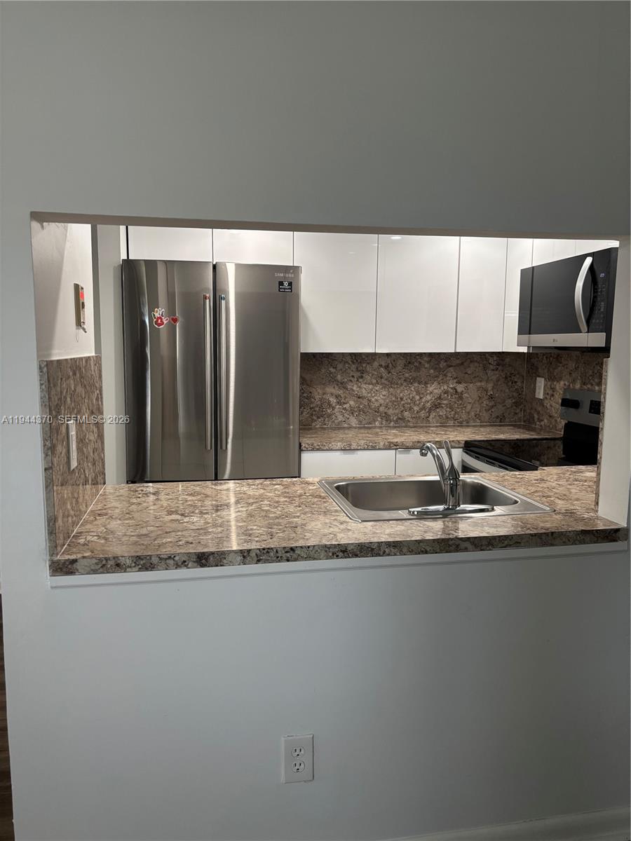 10023 Winding Lake Road, Unit 101 Sunrise, FL 33351 - Photo 4 of 19 a kitchen with stainless steel appliances granite countertop a sink a stove and a microwave oven