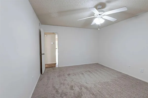 an empty room with a chandelier fan and windows