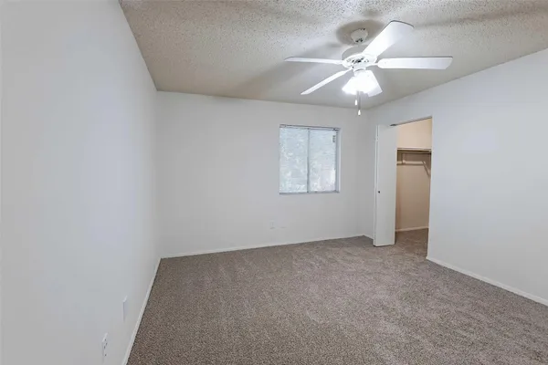 an empty room with a chandelier fan and windows