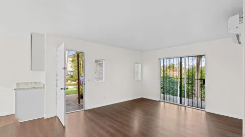 an empty room with wooden floor and windows