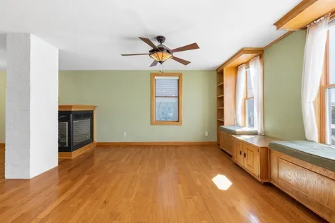 a view of an empty room with window and wooden floor