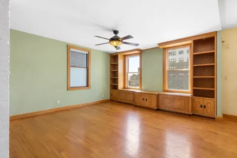 a view of an empty room with a window and dresser