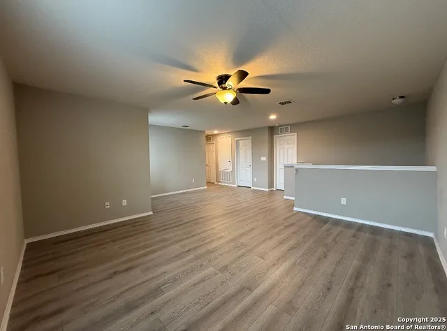 an empty room with wooden floor and a ceiling fan