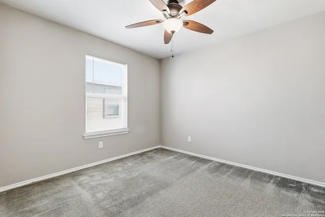 an empty room with a window and a fan