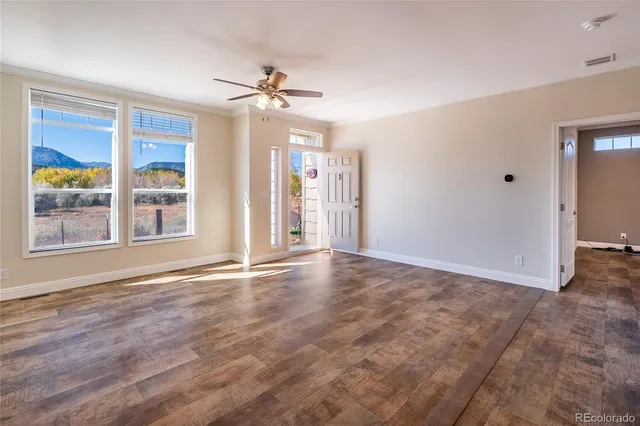 a view of an empty room with a window and wooden floor