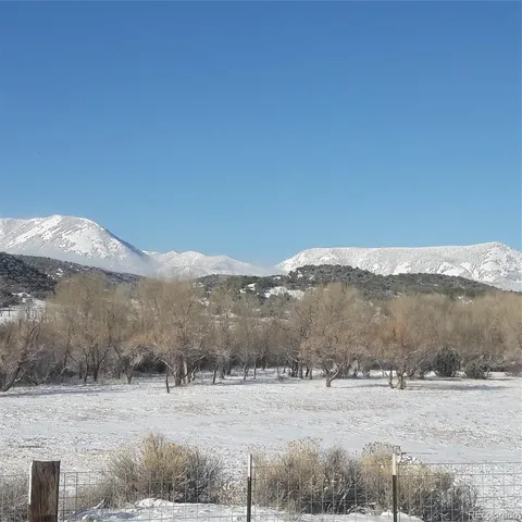 a view of a house with a yard and table and chairs under an umbrella