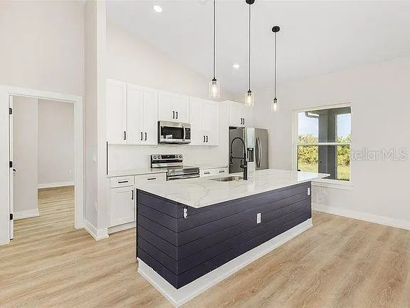 a kitchen with stainless steel appliances kitchen island granite countertop a stove a sink and a refrigerator