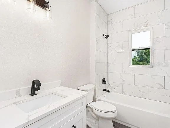 a bathroom with a granite countertop toilet a sink and a bathtub
