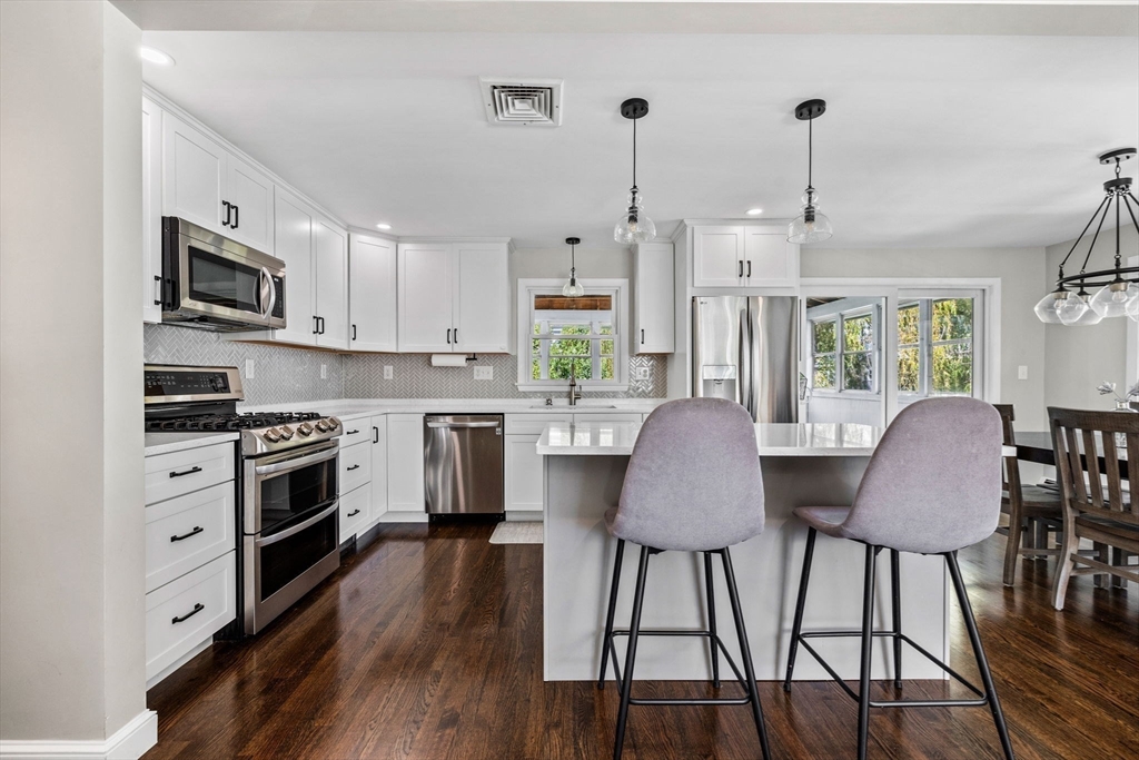 a kitchen with stainless steel appliances a stove a table chairs refrigerator and microwave