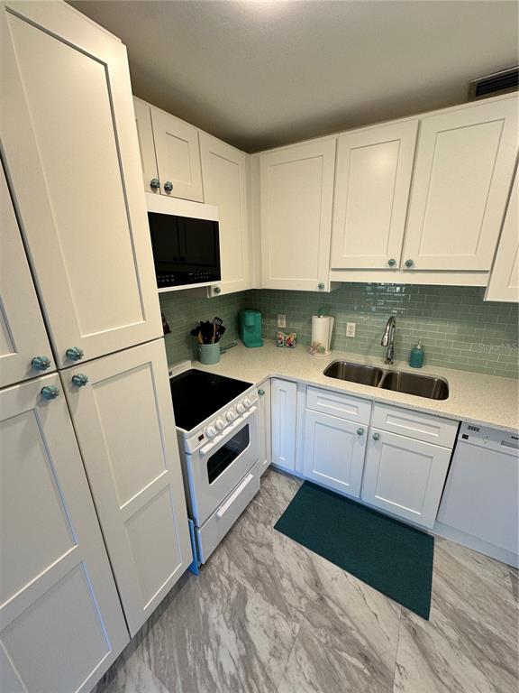 4578 Red Maple, Unit 904 Bradenton, FL 34210 - Photo 22 of 37 a kitchen with granite countertop a sink a white stove a refrigerator a washer and dryer