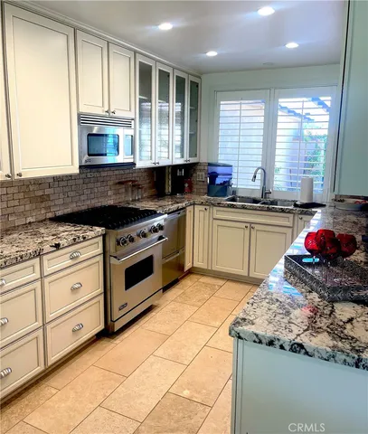 a kitchen with stainless steel appliances granite countertop a stove a sink and a microwave