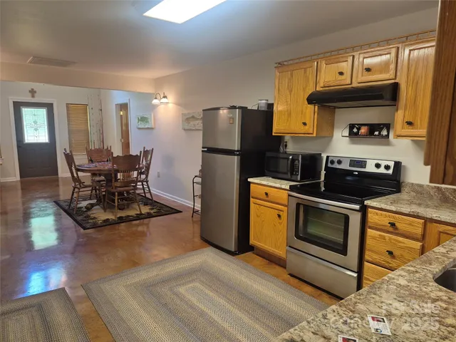 a kitchen with stainless steel appliances granite countertop a stove a refrigerator and a dining table view