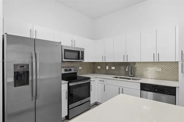 a kitchen with stainless steel appliances a refrigerator stove and white cabinets