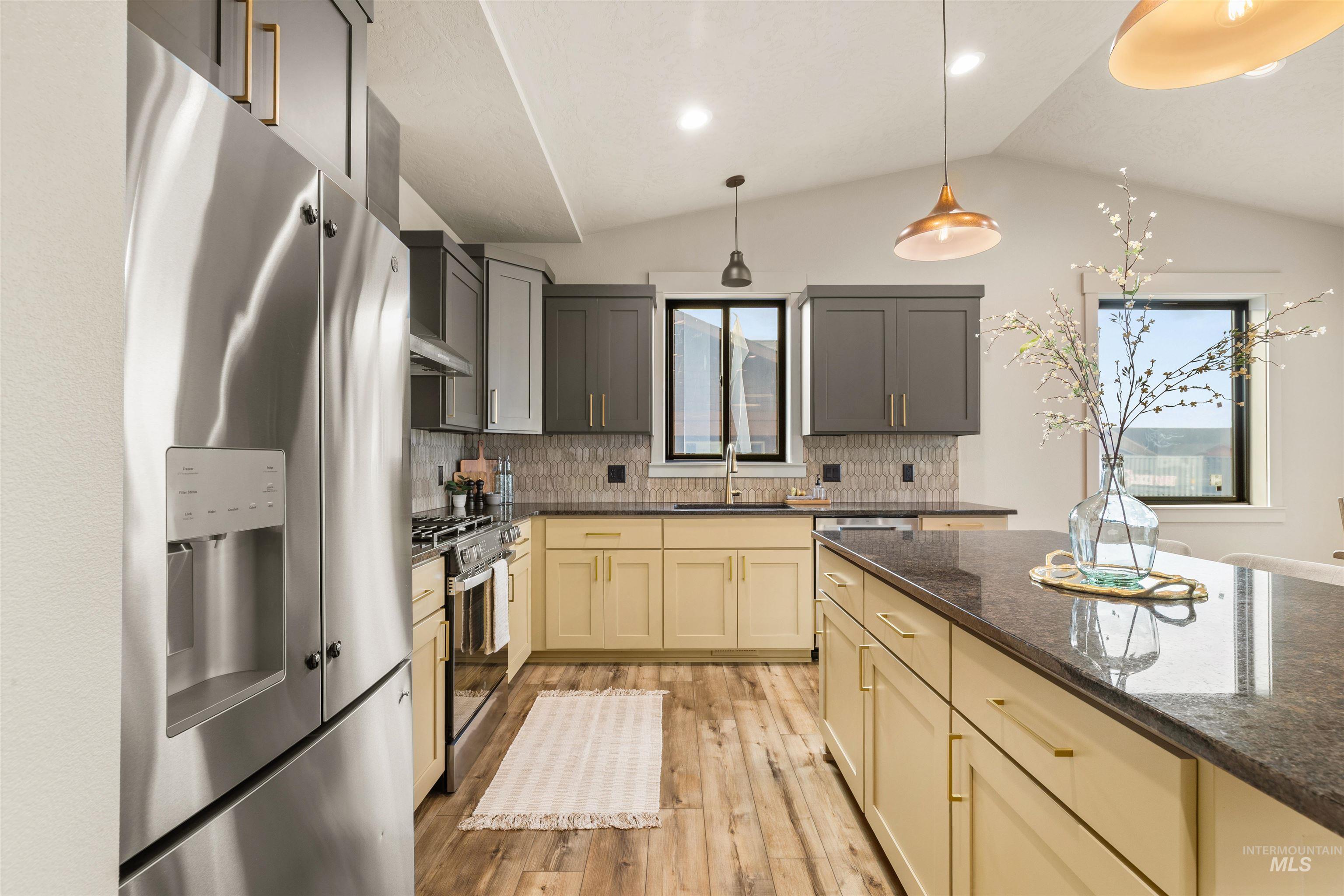 335 Warner Avenue Lewiston, ID 83501 - Photo 15 of 43 Kitchen with stainless steel appliances, dark stone countertops, vaulted ceiling, light wood finished floors, and backsplash