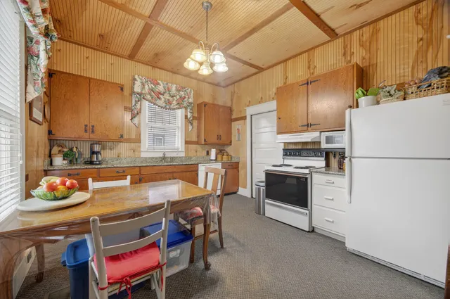 a kitchen with refrigerator a stove a sink and chairs