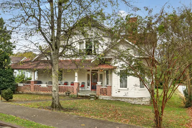 a front view of a house with a garden and tree