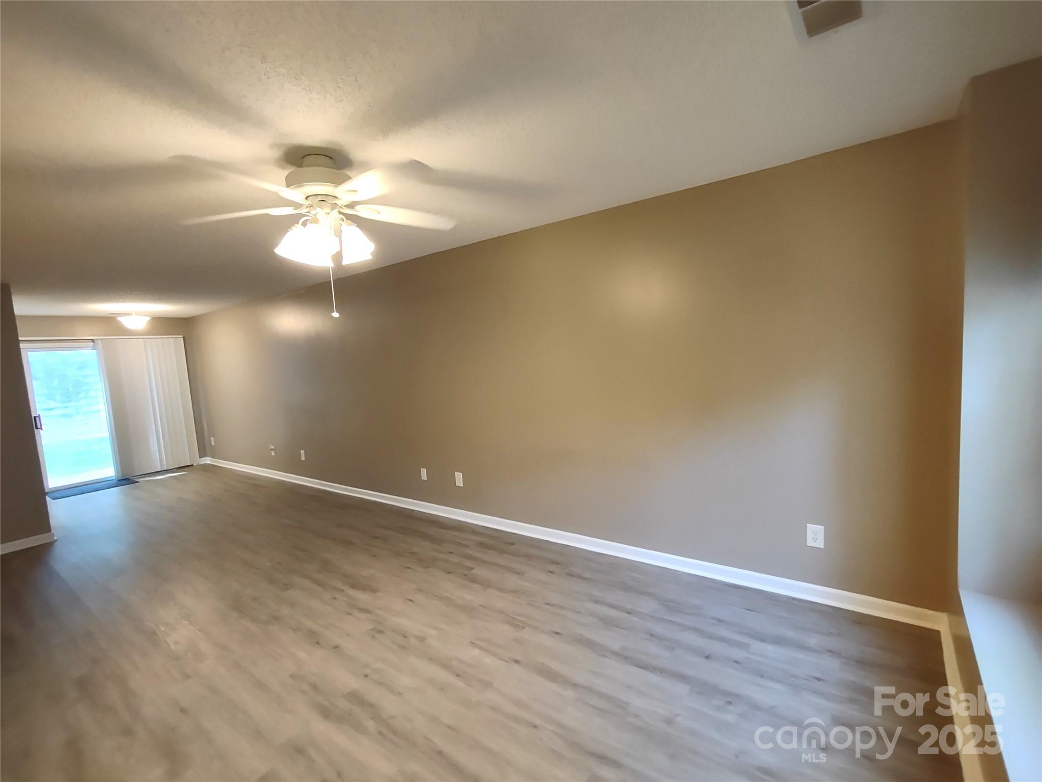 8338 Rudolph Road Charlotte, NC 28216 - Photo 8 of 15 an empty room with wooden floor and chandelier fan