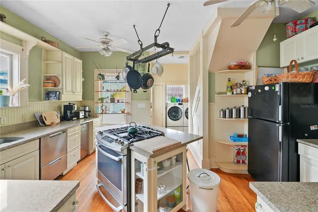 a kitchen with stainless steel appliances granite countertop a stove a sink dishwasher and a refrigerator with wooden floor