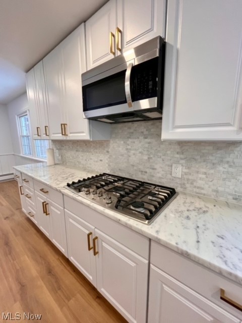 305 Tremont Road Akron, OH 44313 - Photo 9 of 25 Kitchen with white cabinets, appliances with stainless steel finishes, light stone counters, backsplash, and light wood-type flooring