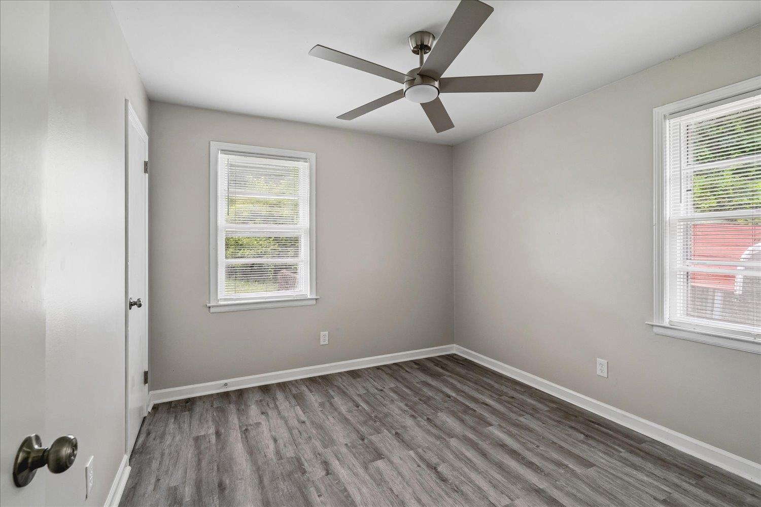 2518 Manchester Road Memphis, TN 38114 - Photo 11 of 23 Spacious room featuring wood-finish flooring, light gray walls, two windows with blinds, a modern ceiling fan, and white trim