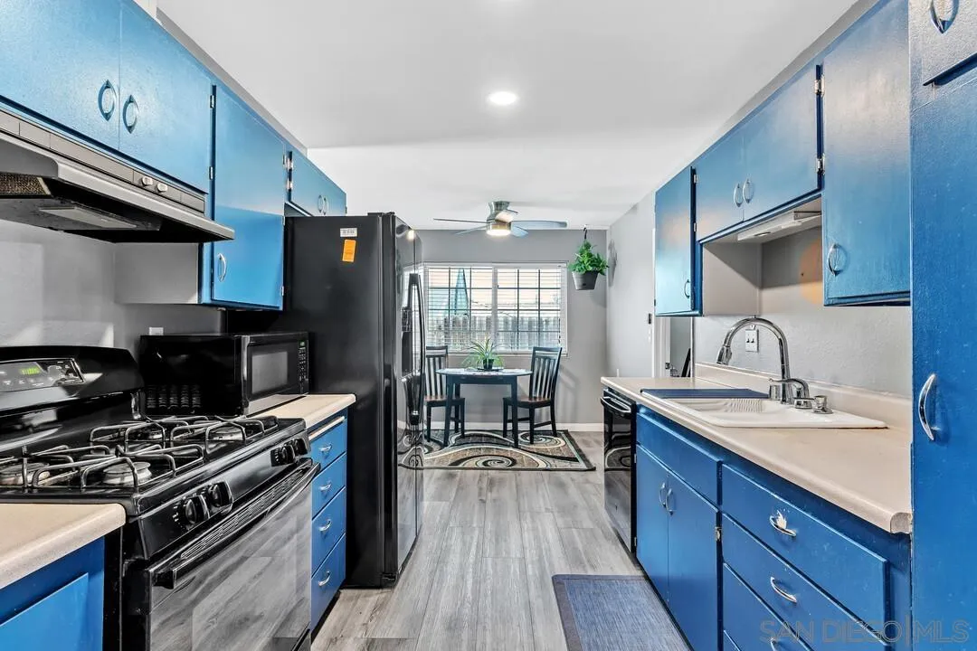 13611 Los Coches Road East El Cajon, CA 92021 - Photo 10 of 34 a kitchen with stainless steel appliances a sink wooden floor and a stove top oven