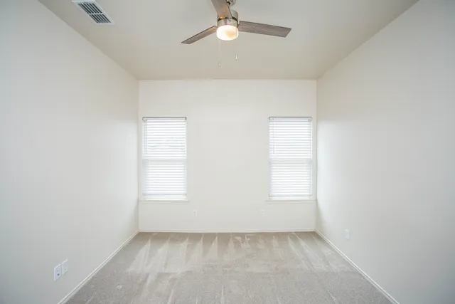 an empty room with windows and fan