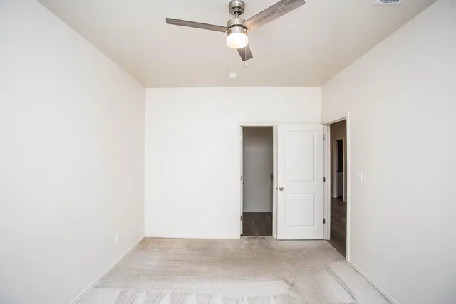 an empty room with closet and a chandelier fan