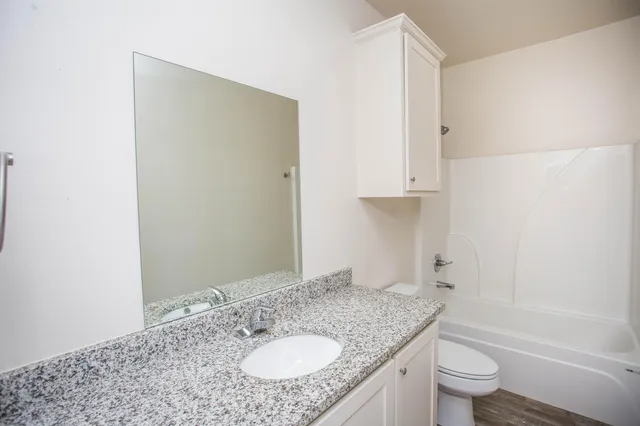 a bathroom with a granite countertop sink toilet and shower