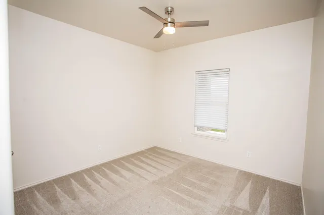 an empty room with a window and ceiling fan