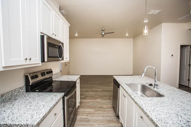 a kitchen with granite countertop a sink and a stove top oven with wooden floor