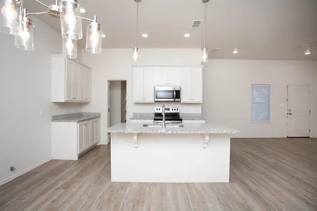 a large kitchen with stainless steel appliances a large counter top a stove a sink dishwasher and a refrigerator