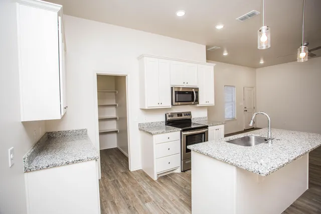 a kitchen with granite countertop a sink and a stove top oven with wooden floor