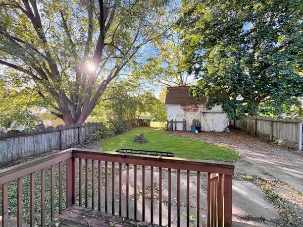 a view of a white house in a yard with large trees
