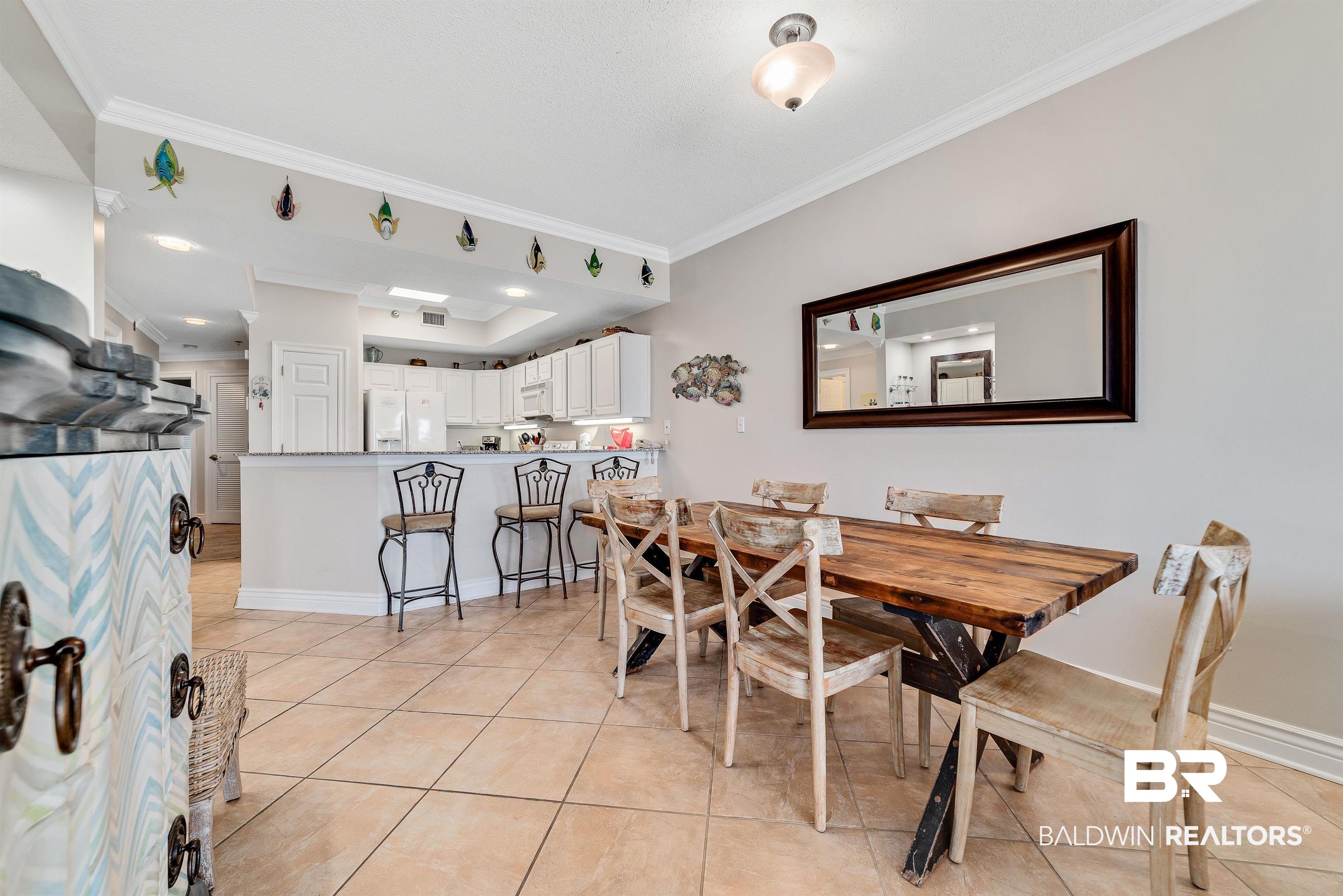 27282 Canal Road, Unit 110 Orange Beach, AL 36561 - Photo 8 of 62 Dining room with light tile patterned floors, ornamental molding, a raised ceiling, and baseboards