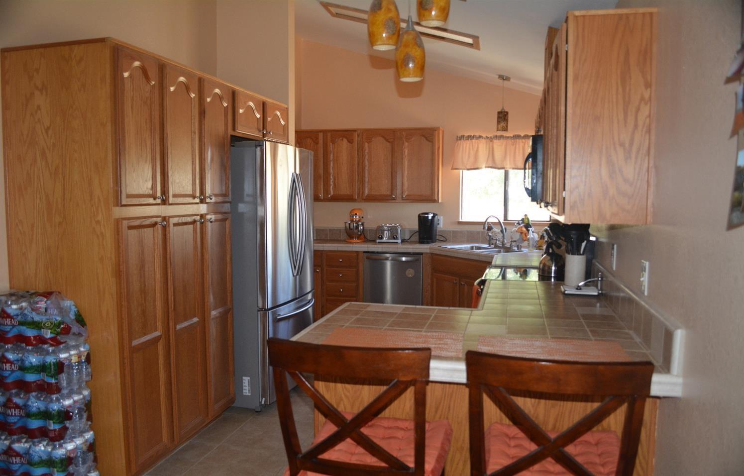 4780 Montiverde Road Mojave, CA 93501 - Photo 14 of 52 a kitchen with a table chairs refrigerator and cabinets