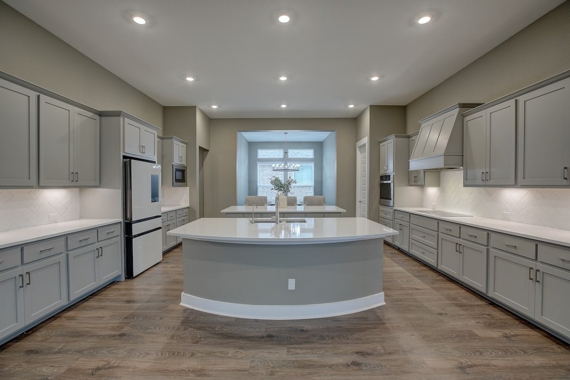 a view of a kitchen with kitchen island a sink stainless steel appliances and cabinets