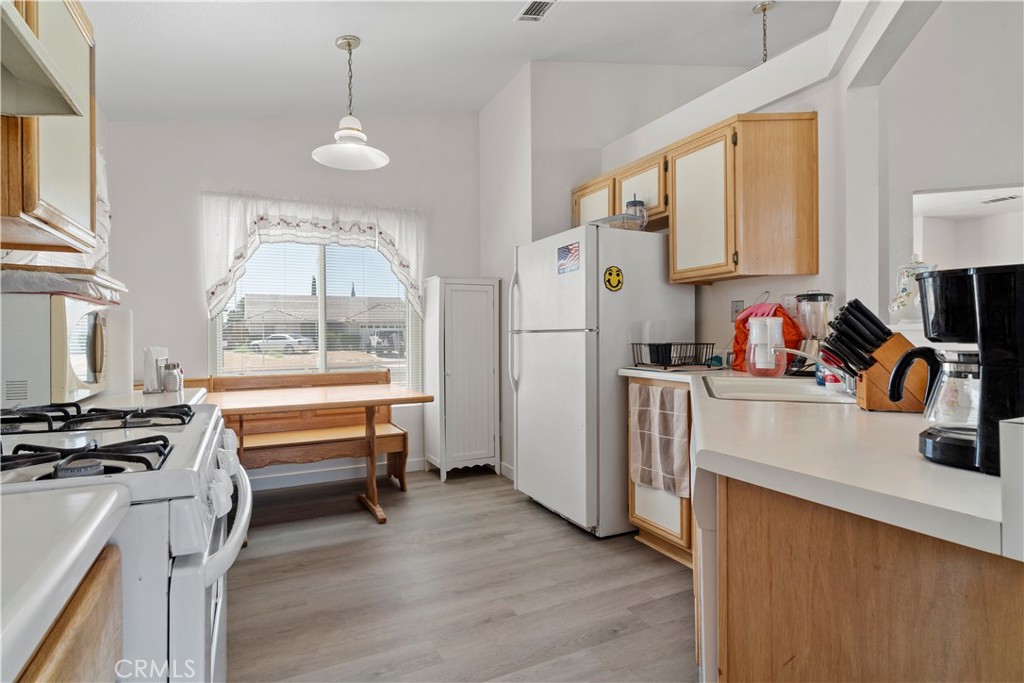 11688 Cornell Street Adelanto, CA 92301 - Photo 10 of 40 a kitchen with a refrigerator a stove a sink and a dining table with wooden floor