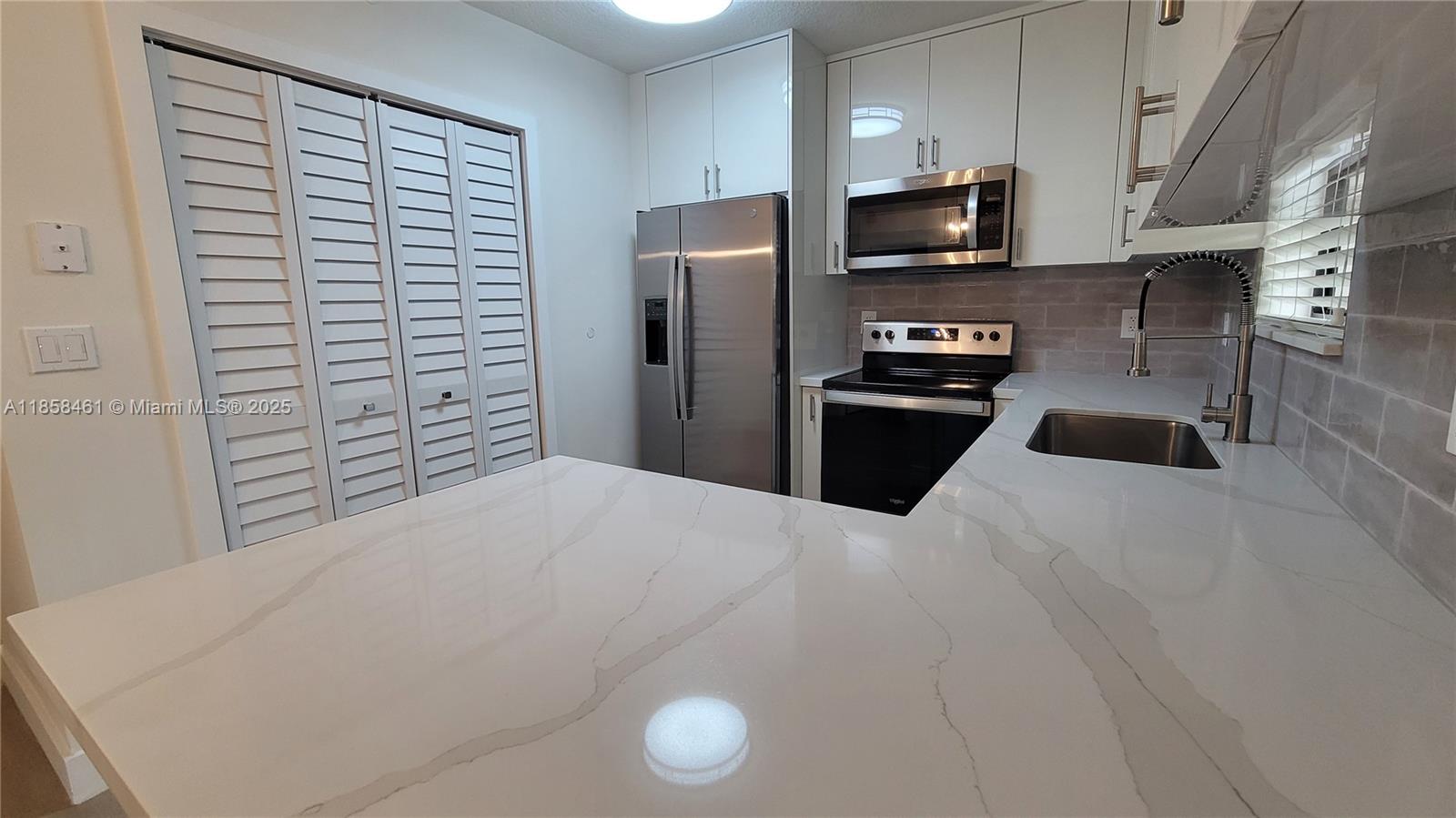 22731 Southwest 88th Place, Unit 101 Cutler Bay, FL 33190 - Photo 11 of 59 a kitchen with a refrigerator and a stove top oven